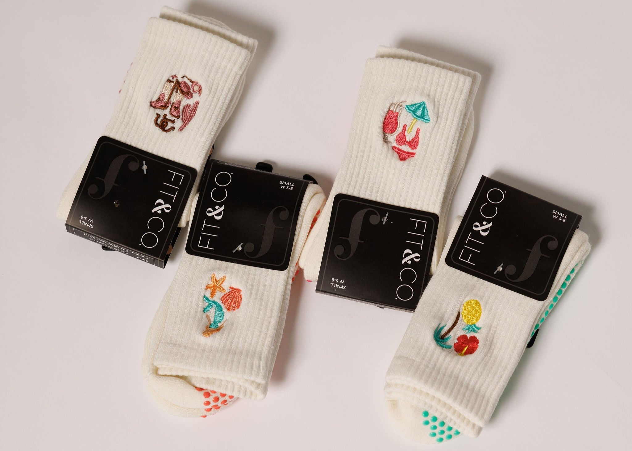 Four pairs of grip socks with brand logo packaging on a light gray background